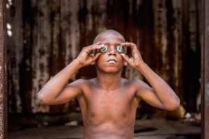 Cuba, Havanna, Boy holding bottle caps before his eyes, 'looking into the future', Cuba, Havanna, Boy holding bottle caps before his eyes, 'looking into the future',